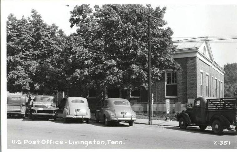 Black and white photo of a street view in Livingston, Tennessee, showing vintage cars parked along the curb in front of the U.S. Post Office and a large tree.