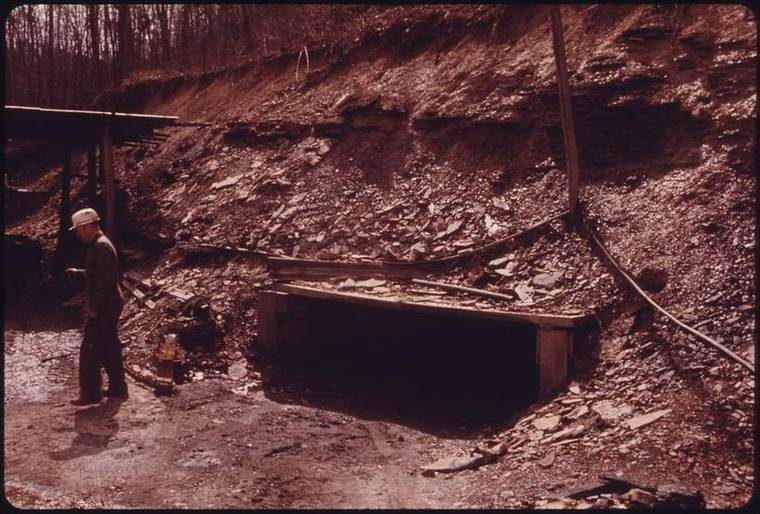 Color portrait of a retired coal-mine operator standing at the overgrown, timber-framed entrance of the mine he once ran, part of Jack Corn's 1974 DOCUMERICA documentation of the collapsed coal-mining economy of the Wilder-Davidson-Crawford mining complex.